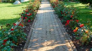 un chemin en briques dans un jardin avec des fleurs rouges dans l'établissement Vila Raj, planina Ozren - Sokobanja, à Sokobanja