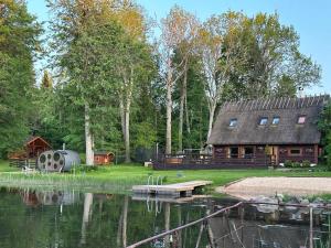 a cabin next to a lake with a house at Tammeveski Holiday House in Kobruvere