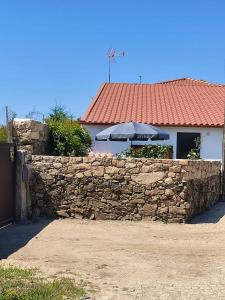 a stone wall with an umbrella in front of a building at One bedroom house with enclosed garden and wifi at Parada in Parada