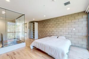 um quarto com uma cama branca e uma parede de vidro em Modern Loft-Style Townhouse in Los Angeles em Los Angeles