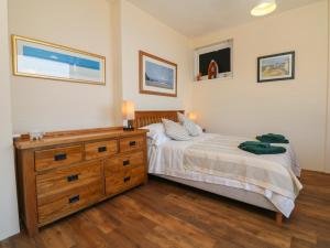 a bedroom with a bed and a wooden dresser at At the Bay Apartment in Ilfracombe