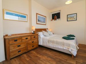 Un dormitorio con una cama y una cómoda de madera. en At the Bay Apartment, en Ilfracombe
