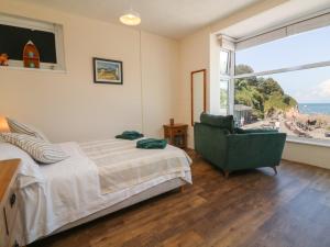 a bedroom with a bed and a chair and a window at At the Bay Apartment in Ilfracombe