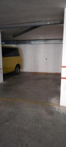 een geel busje geparkeerd in een parkeergarage bij El Descanso del Sol - Apartamento en Pirineos in Plan