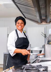 a woman in a kitchen preparing food on a spatula at ibis Porto Alegre Moinhos de Vento in Porto Alegre