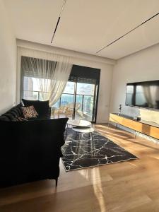 a living room with a black couch and a tv at panoramic apartment EdenTower in Bat Yam
