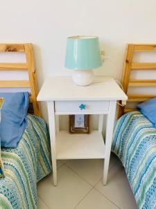 Sa Suergia Apartment في فيلاسيميوس: طاولة بيضاء عليها مصباح بجانب سريرين