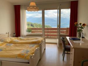 a bedroom with two beds and a desk and a window at Hotel Haltenegg in Heiligenschwendi