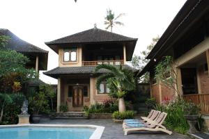 a house with a swimming pool in front of it at Klub Kokos Bungalows in Ubud