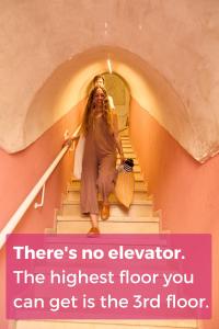 a woman walking down a stairs with a sign that reads there is no elevator at Pink & Blondie - Smart Hotel by Loginn Tel Aviv in Tel Aviv