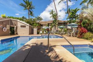 a swimming pool in front of a house with palm trees at Grand Champions 55, Beautiful Renovation, Split AC in Wailea