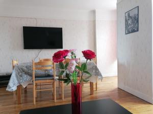 un salon avec une table et des roses dans un vase rouge dans l'établissement Appartement Ilianah, à Domfront