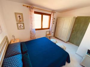 Sa Suergia Apartment في فيلاسيميوس: غرفة نوم بسرير ازرق ونافذة