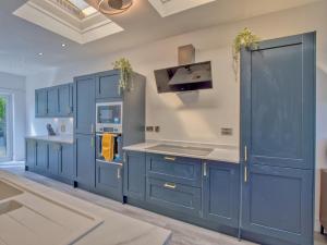 a blue kitchen with white counters and blue cabinets at Seamill Cottage in West Kilbride