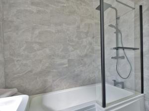 y baño con ducha y bañera blanca. en Seamill Cottage en West Kilbride
