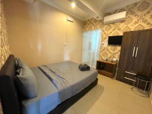 um quarto com uma cama e uma televisão num quarto em MJ inn em Ranau