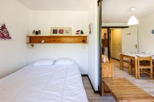 een slaapkamer met een wit bed en een tafel bij Les Mélèzes - Appt à Serre Chevalier in Saint-Chaffrey