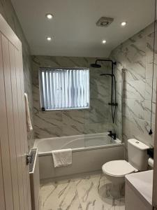 a bathroom with a tub and a toilet and a sink at Modern 3 Bedroom home near Birmingham Airport & NEC in Sheldon