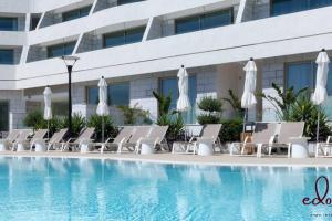 a row of lounge chairs next to a swimming pool at דירה משפחתית מרווחת במתחם סי סייד - By Edomlux in Eilat +8 photos