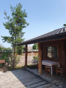 a cabin with a bench on a wooden deck at Eco dom v lesu in Bila Krynytsya