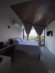 a bedroom with a bed and a large window at CHALE VILAALICE in Monte das Gameleiras