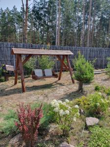 einen hölzernen Picknicktisch in einem Garten mit einem Zaun in der Unterkunft Eco dom v lesu in Bila Krynytsya