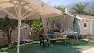 um pátio com um guarda-chuva e um trampolim em דירת חדר נעימה במיקום פסטורלי em Qiryat Shemona