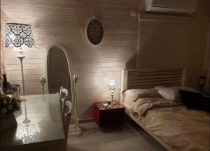 1 dormitorio con 1 cama y reloj en la pared en דירת חדר נעימה במיקום פסטורלי, en Kiryat Shemona