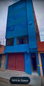 a blue building with red doors on a street at UMERSA SUITE HOTEL in Espinar