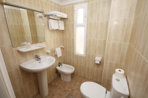 a bathroom with a sink and a toilet and a mirror at Apartamentos Niza in Benidorm