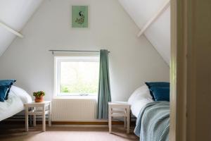 een slaapkamer op zolder met 2 bedden en een raam bij Vakantiehuis Veluwe Bosuil Nunspeet in Nunspeet