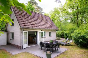 een klein wit huis met een tafel en stoelen bij Vakantiehuis Veluwe Bosuil Nunspeet in Nunspeet