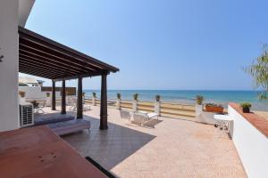 a patio with a table and chairs on the beach at Le Sorelle Villa sul mare in Porto Empedocle