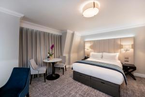 um quarto de hotel com uma cama, uma mesa e cadeiras em Tower Residences by Blue Orchid em Londres