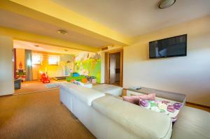 ein Wohnzimmer mit einem weißen Sofa und einem Flachbild-TV in der Unterkunft Hotel Bystrina in Demänovská Dolina