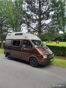 RETRO CAMPER HIRE LTD Campervan Hire Company "Travel Throughout Ireland " في دبلن: سيارة فان بنية متوقفة على جانب الطريق