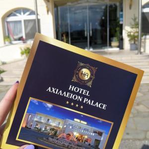 een persoon die een hotel avalon paleis bord omhoog houdt bij Achillion Palace in Kalambaki