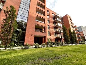 a large brick building with a grass field in front of it at Scala Apartments Gdańsk by Acznowy & Parking in Gdańsk