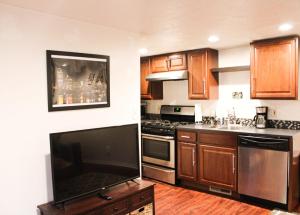 een keuken met houten kasten en een flatscreen-tv bij 1 Bed Apt - Amazing Location 1 Block to Carson St in Pittsburgh