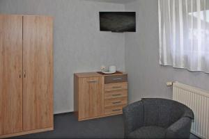 a room with a chair and a wooden dresser at Ferienwohnung Brandshagen in Reinberg