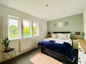 a bedroom with a large bed and two windows at Royal Calderdale Lodge in Halifax