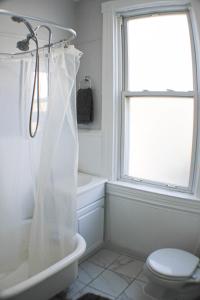 a white bathroom with a toilet and a window at 3 BR - Off Street Parking - Amazing View Nearby in Pittsburgh