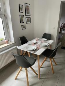 a dining room table with chairs and a white table and plates at Modern eingerichtet-stadtnah-Ferienwohnung mit Geschirrspüler und Waschmaschine in Friedland