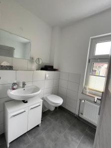 biała łazienka z umywalką i toaletą w obiekcie Modern eingerichtet-stadtnah-Ferienwohnung mit Geschirrspüler und Waschmaschine w mieście Friedland