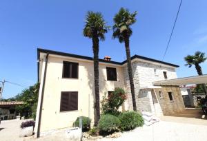 a house with two palm trees in front of it at Mia apartments in Savudrija