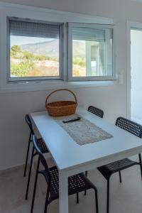 uma mesa branca e cadeiras com duas janelas em STO LOFO Apartments Kalyvia-Limenaria Thassos em Limenaria