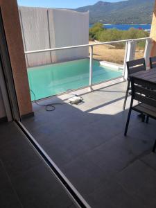 balcón con mesa y piscina en Casa campa lumba en Propriano