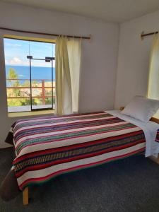 1 dormitorio con cama y ventana grande en Inca lodge - Amantani en Ocosuyo