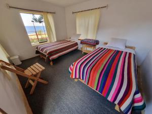 Habitación con 2 camas y ventana en Inca lodge - Amantani, en Ocosuyo