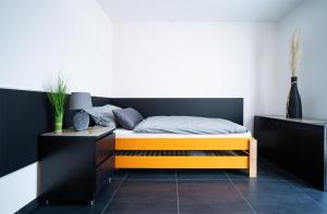 1 dormitorio con 1 cama con cabecero negro y naranja en Blauer Stein 7a WH01 - Apartment 3 SZ, 5 Betten, en Pulheim